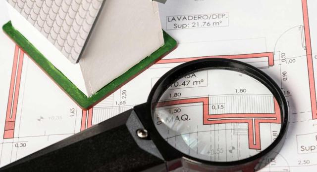 El Ayuntamiento puede comprobar el valor de adquisición declarado en el IIVTNU si no refleja el valor de mercado del inmueble en la fecha de adquisición hereditaria. Imagen de una lupa sobre el plano con medidas de una casa