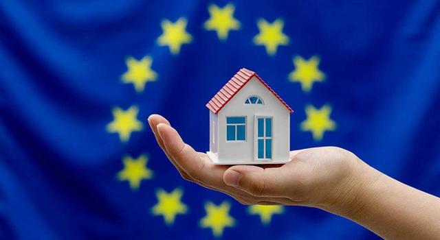 Parlamento Europeo: Incentivos fiscales, renovación residencial y menos papeleo frente a la crisis de la vivienda. Imagen de una casita en la palma de una mano con la bandera de la UE por detrás