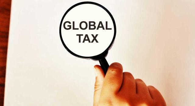 Tributación mínima global y planificación fiscal internacional: lo que deben saber los asesores fiscales. Imagen de una lupa en una mano en la que se puede leer Global Tax