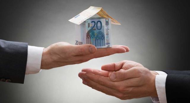 Afectación de participaciones de una holding en una filial con la misma actividad de arrendamiento de inmuebles pero de forma externalizada Aplicación de la reducción en ISD a las participaciones de una holding en una filial que desarrolla la misma actividad de arrendamiento de inmuebles, aunque hubiera externalizado su gestión. Imagen de una mano ofreciendo a otra mano una casa hecha de billetes