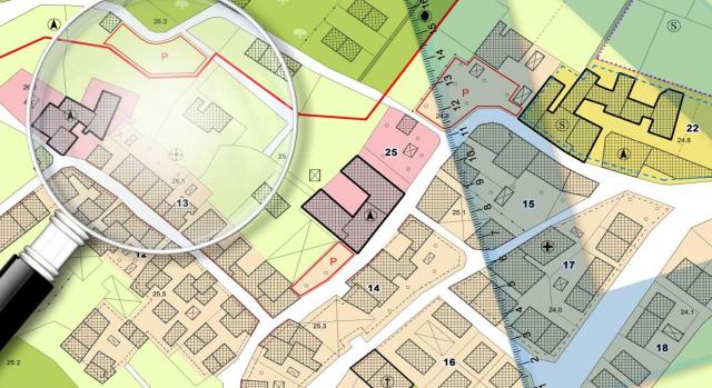 La Audiencia Nacional establece que la transmisión de parcelas está sujeta al IVA al actuar la transmitente como empresario mediante intervenciones activas en derechos urbanísticos. Imagen de la cartografía de una parcelas con una lupa y regla encima