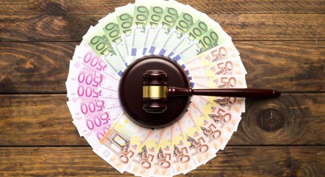 Las cargas previas asumidas en la adquisición de un inmueble en subasta pública no incrementan el valor de adquisición ni se consideran gastos inherentes a efectos del IRPF. Imagen de un mazo de juez rodeado de billetes de euros