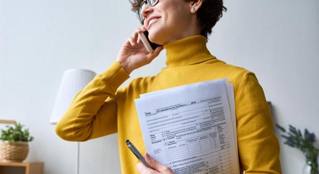 Medidas Fiscales aprobadas en Extremadura. Imagen de mujer con documentación hablando por teléfono