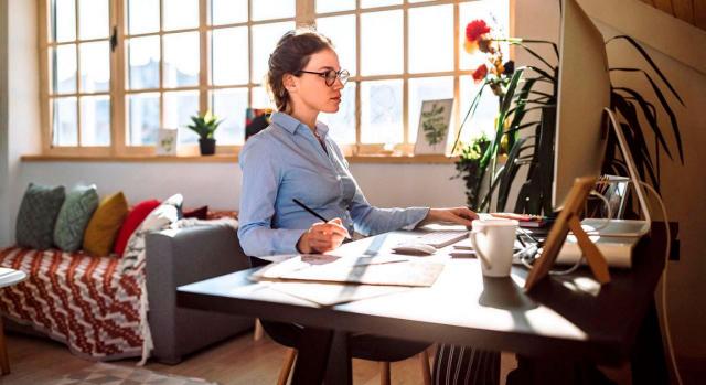 Ley del trabajo a distancia: medidas tributarias. Imagen de una chica teletrabajando desde el salón de su casa