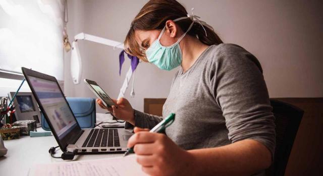 Modelos IRPF e IP 2019. Mujer con una mascarilla trabajando frente a un ordenador