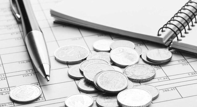 ¿Es exigible el informe técnico-económico cuando las modificaciones de ordenanzas fiscales se limitan a la mera actualización de sus tarifas por aplicación de la variación del IPC? Imagen de monedas, boli y cuaderno en tonos grises