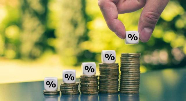 Resulta procedente la deducción en el IRPF del importe efectivamente retenido en el extranjero por dividendos, sin sujeción al límite del 15% que establen los convenios para evitar la doble imposición. Imagen de montoncitos de monedas haciendo una gráfica con dados con porcentaje en cada montón