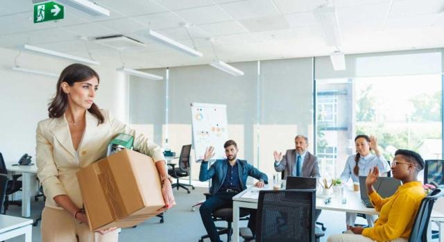 El TSJ de Madrid diferencia entre complementos salariales e indemnización por despido generada en un período inferior a dos años, en relación con la reducción del 30% para rendimientos irregulares. Imagen de una mujer con sus pertenencias en una caja mientras se despide de sus compañeros de trabajo