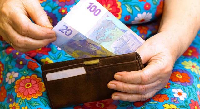 El TS sobre la naturaleza jurídica del copago por servicios de atención a la dependencia. Imagen de una mujer metiendo dinero en una cartera