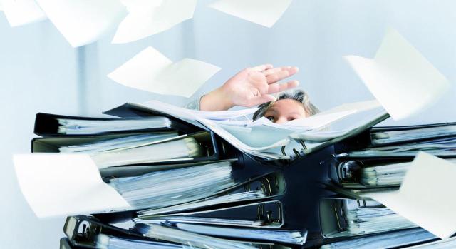 Existe una nítida desconexión entre la realidad de los hechos configuradores de la pretensión y el contenido en el programa INFORMA El TS inadmite como causa exculpatoria de la responsabilidad tributaria el criterio contenido en el programa INFORMA, pues el recurrente no tenía derecho a la exención en el IEDMT y su declaración no fue conforme con la realidad. Imagen de una mujer detrás de una pila de carpetas y de trabajo