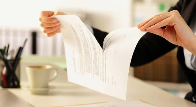 Derogación de la prórroga de las medidas fiscales en IRPF, IS e IVA aprobadas en el RDLey 2/2026 que no ha sido convalidado en el Congreso de Diputados. Imagen de una mujer en su escritorio rompiendo u npapel