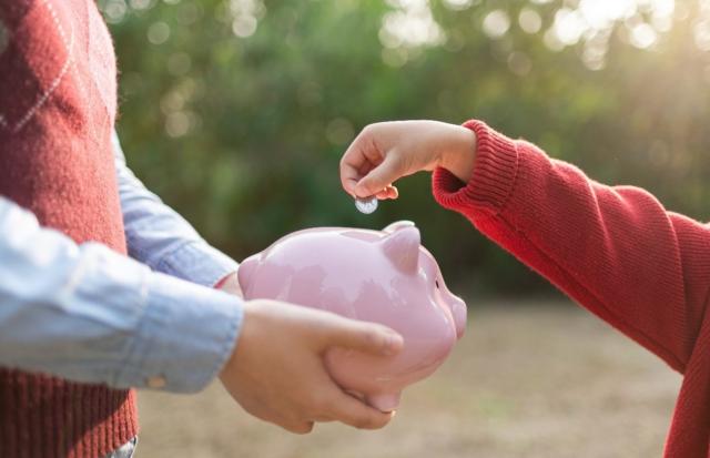 A efectos de computar el plazo de prescripción, se ha de tener en cuenta el previo devengo del impuesto y la finalización del plazo de declaración o autoliquidación derivado de este. Imagen de el brazo de un niño hechando monedas en un cerdito rosa