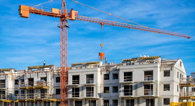 La bonificación en la cuota del ICIO para la construcción de viviendas de protección oficial solo se podrá conceder previa solicitud del sujeto pasivo en las condiciones y dentro del plazo expresamente previsto en la ordenanza municipal. Imagen de una grua en una zona de construcción de edificios