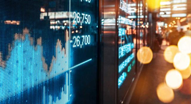 Proyecto de Orden que prevé cambios en los Modelos 780 y 781 del impuesto sobre el margen de intereses y comisiones de determinadas entidades financieras. Imagen de números bursátiles financieros y reflejos de la luz de la ciudad