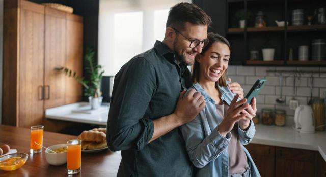 La inscripción de las parejas de hecho en el Registro es preceptiva para aplicar los beneficios fiscales. Pareja feliz mirando un teléfono movil