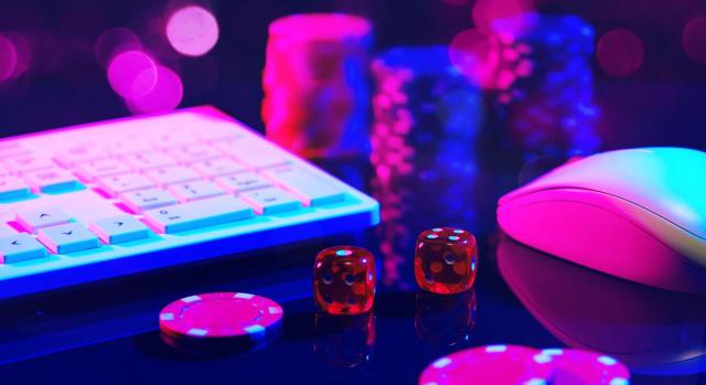 IRPF: Compensación de las pérdidas patrimoniales del juego con el importe de las ganancias obtenidas en el mismo período impositivo. Dados rojos sobre una superficie rosa con un teclado y un ratón de portátil