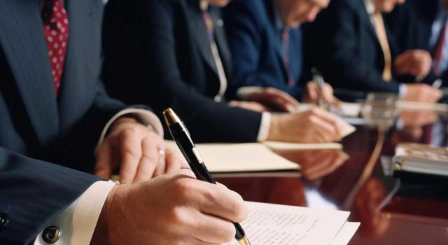 Los atrasos salariales no pueden imputarse en IRPF en el ejercicio en que adquirió firmeza la sentencia colectiva, sino posteriormente, con la sentencia individual. Imagen de personas firmando y revisando documentos