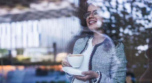 Plazos ampliados. Imagen de una empresaria con un café en la mano mirando a través de una ventana