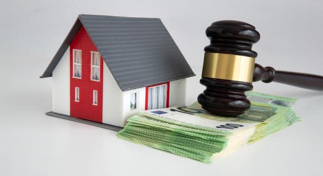 DGT: Valor de adquisición a efectos de la plusvalía (IIVTNU) de una vivienda adquirida como parte de un legado. Casa en miniatura, fajo de dinero y mazo que simbolizan la ley