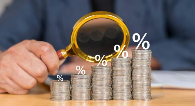 Bizkaia aprueba su norma foral del Impuesto sobre el margen de intereses y comisiones de determinadas entidades financieras. Hombre de negocios sosteniendo lupa con símbolo de porcentaje y flecha hacia arriba