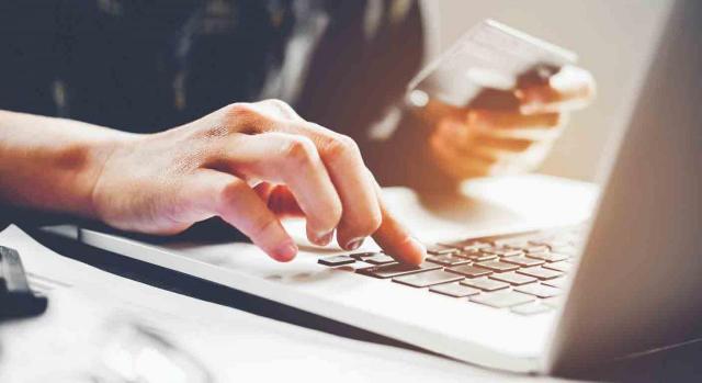 Pago entidades colaboradoras Pago entidades colaboradoras. La mano de un hombre sobre las teclas de un portátil y una tarjeta de crédito en la otra