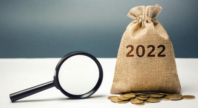 Proyecto de Ley de PGE para 2022: Medidas fiscales . Imagen de un saco con el 2022 y monedas debajo y una lupa
