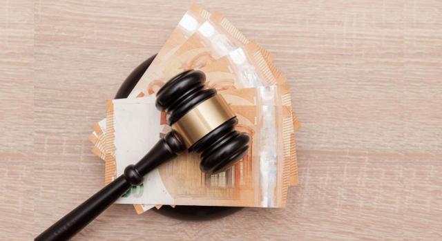 La Audiencia Nacional estima que las provisiones por responsabilidades derivadas de litigios son deducibles en el IS La Audiencia Nacional estima que las provisiones por responsabilidades derivadas de litigios son deducibles en el IS. Vista superior de mazo judicial sobre un fajo de billetes sobre mesa de madera