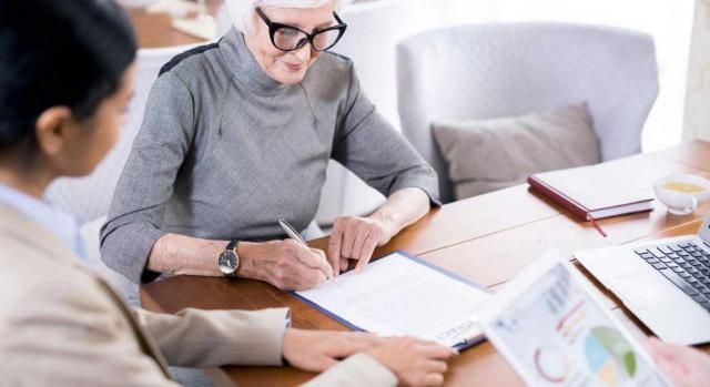 reducción 40% planes pensiones. Imagen de una mujer firmando documentos