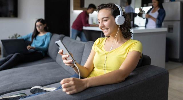 Reducción por alquiler de vivienda en contratos inferiores a un año. Imagen de chica joven escuchando música en el sofá de una casa compartida