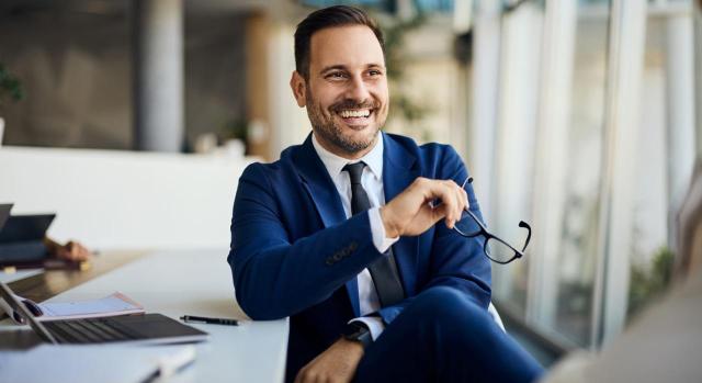 Régimen de impatriados: solapamiento entre cese laboral y nombramiento como administrador. Hombre sonriente sosteniendo gafas en la mano en un entorno de oficina