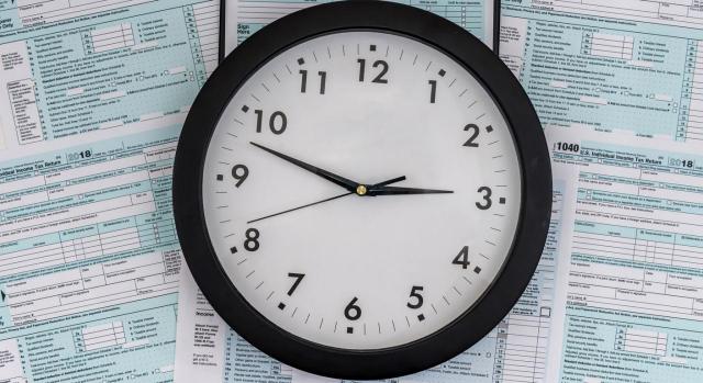 Imagen de un reloj sobre formularios de sancion agente tributario