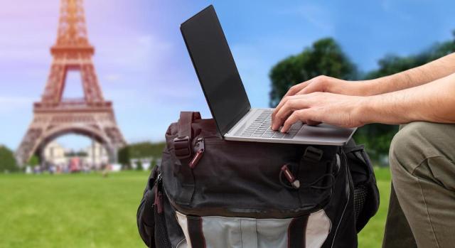 IRPF: Imputación de rentas inmobiliarias por la vivienda habitual en España de los contribuyentes acogidos al régimen de impatriados del IRPF IRPF: Imputación de rentas inmobiliarias por la vivienda habitual en España de los contribuyentes acogidos al régimen de impatriados del IRPF. Chico trabajando sobre una mochila en un parque con la torre Eiffel al fondo