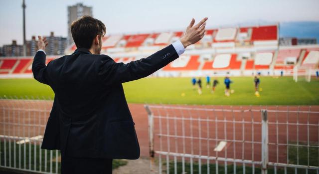 Residencia fiscal entrenador de futbol de espaldas frente a un estadio