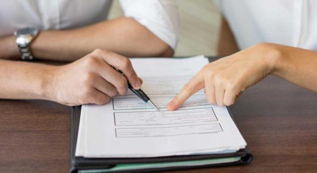 Invalidez del procedimiento de comprobación limitada por falta de declaración expresa de caducidad del anterior procedimiento de control de presentación de declaraciones Invalidez del procedimiento de comprobación limitada por la falta de declaración expresa de caducidad del anterior procedimiento de control de presentación de declaraciones. Imagen de las manos de dos personas señalando un documento en conjunto