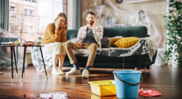 No cabe aplicar el tipo reducido del 10% de IVA a los servicios de renovación o reparación de viviendas particulares abonados por la compañía aseguradora, y a efectos de sanción cabe aplicar la interpretación razonable de la norma. Imagen de una pareja en su salón viendo como cae agua de una gotera