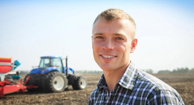 Tributación jóvenes agricultores. Imagen de un hombre joven cerca de un tractor