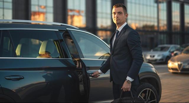 IS e IVA: adjudicación a socio de vehículo totalmente amortizado IS e IVA: adjudicación a socio de vehículo totalmente amortizado. Hombre joven abriendo la puerta de un coche de gama alta de color negro