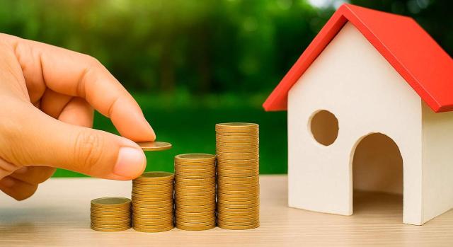 IRNR: rentas por alquiler impagadas. Maqueta de vivienda y monedas apiladas