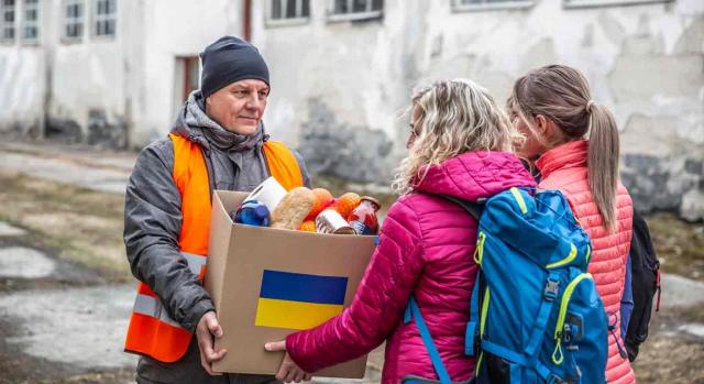 Nuevas deducciones Aragón ucrania. Un voluntario entrega una caja de alimentos con la bandera de Ucrania a dos mujeres